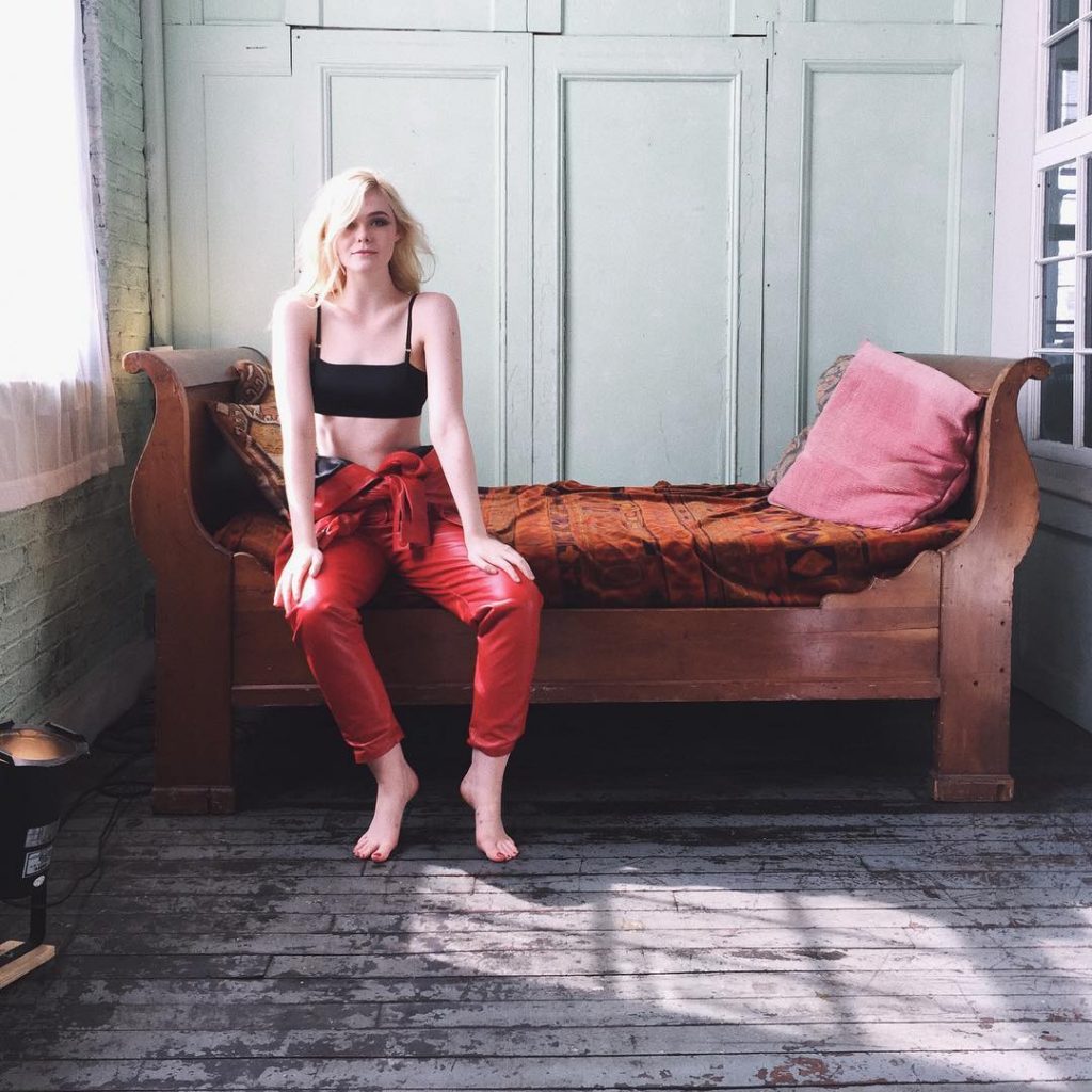 Elle Fanning poses in a  black bra on red couch for L’Oreal Paris makeup campaign 