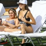 Madison Beer in a black bathingsuit and white hat