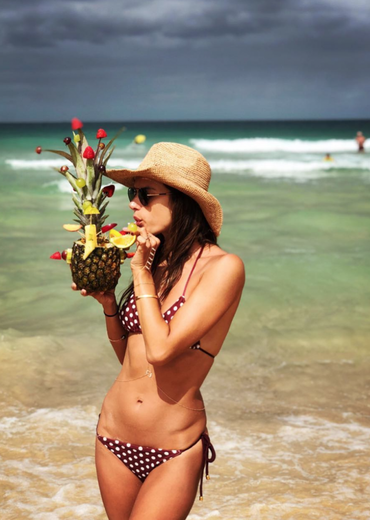 Alessandra Ambrosio sucks a straw in her bikini on the beach