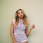 Tinashe poses in a pink and white stripped bodysuit