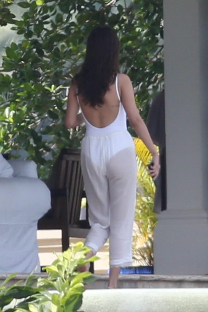 Selena GOmez in sheer white pants and a white swimsuit in Jamaica