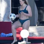 Iskra Lawrence in a green bikini kicking a soccer ball