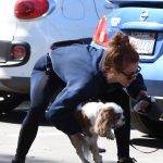 Julian Hough in leggings picking up her dog