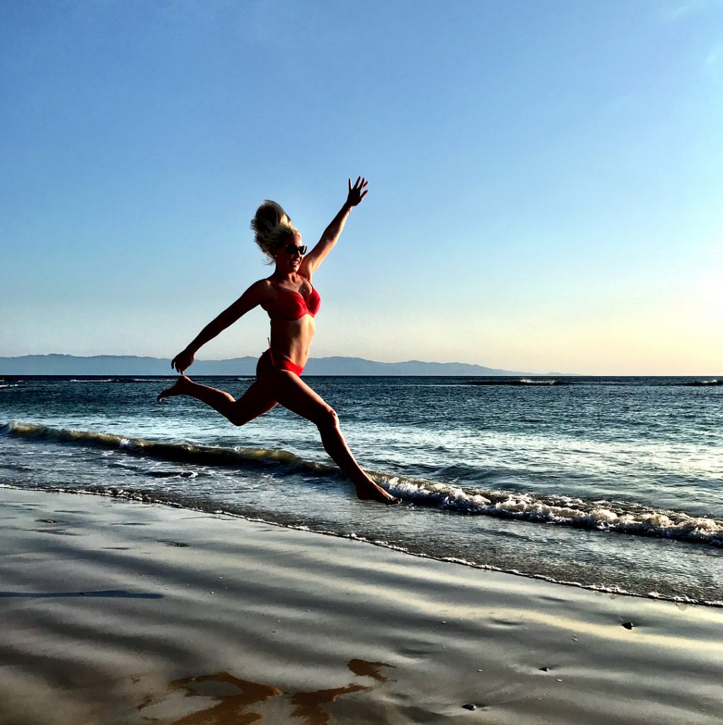 Katherine Heigl in a red bikini jumping on the beach